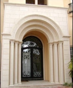 An Entry with decorative front porch columns for the arched stonework over them.